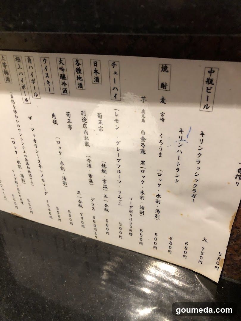 A printed menu board displaying various beer, sake, and other alcoholic beverages with prices in yen.