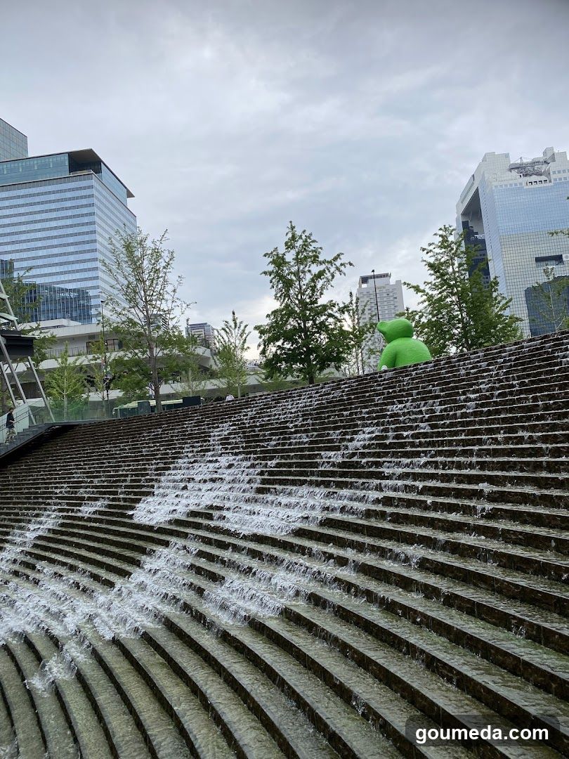 Waterfall feature in urban plaza with green sculpture