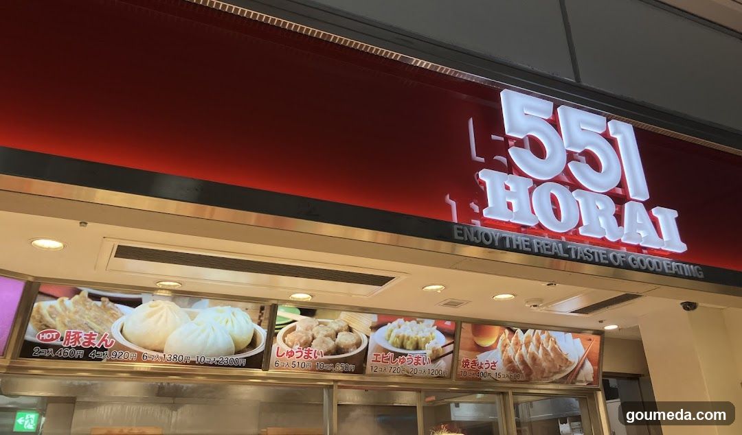 A storefront with a red sign displaying '551 HORAI' and the tagline 'ENJOY THE REAL TASTE OF GOOD EATING'. Below, there are menu boards showcasing various food items like gyoza, dumplings, and other Japanese dishes with prices listed in yen.