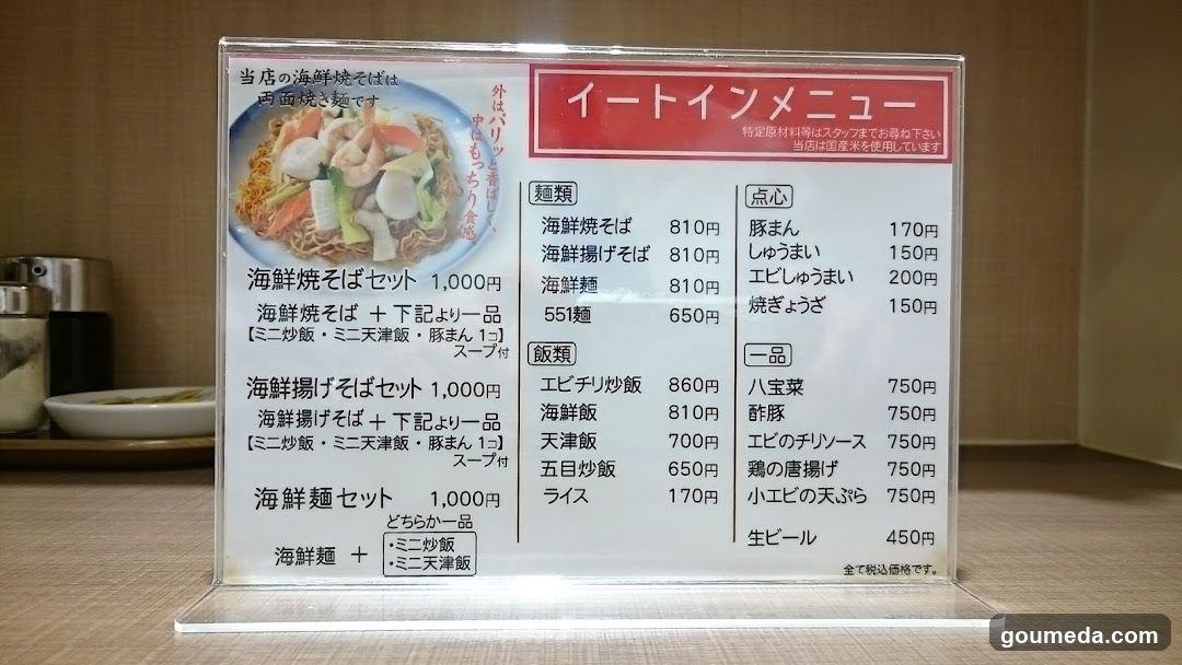 A clear acrylic menu board displaying a Japanese seafood restaurant's offerings, including sets of seafood soba and noodles with rice options.