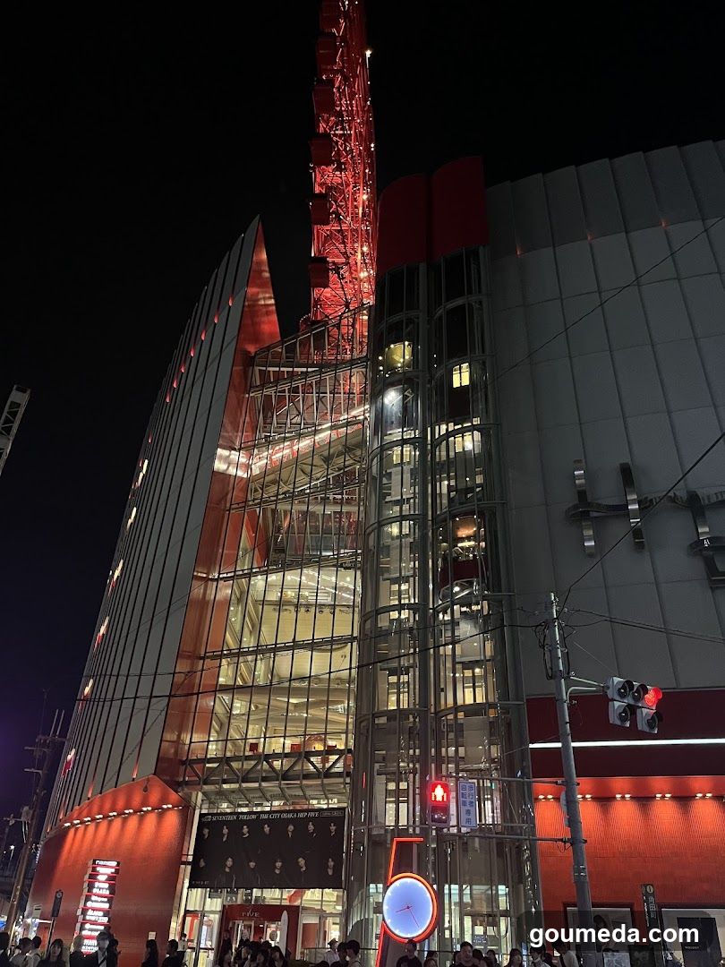 Night view of a modern building with illuminated tower and glass facade