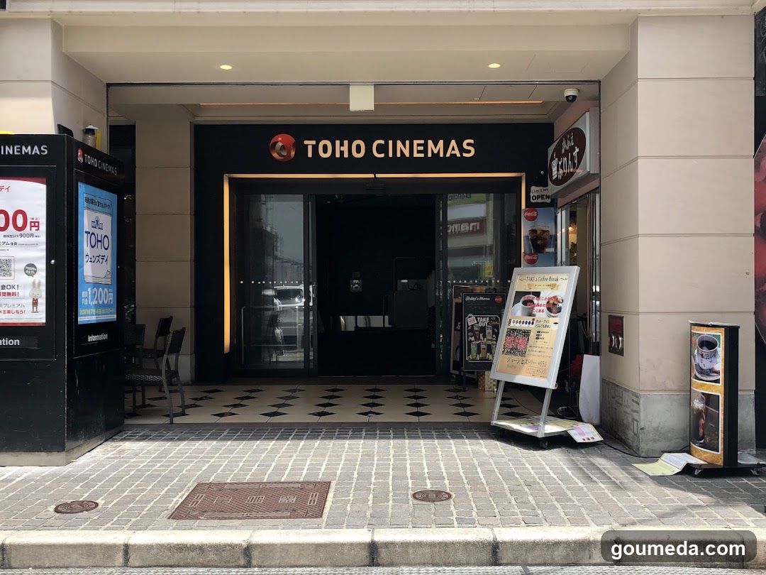 Photo of the physical exterior entrance storefront facade with visible signage ON the building showing TOHO CINEMAS logo and name above glass doors.