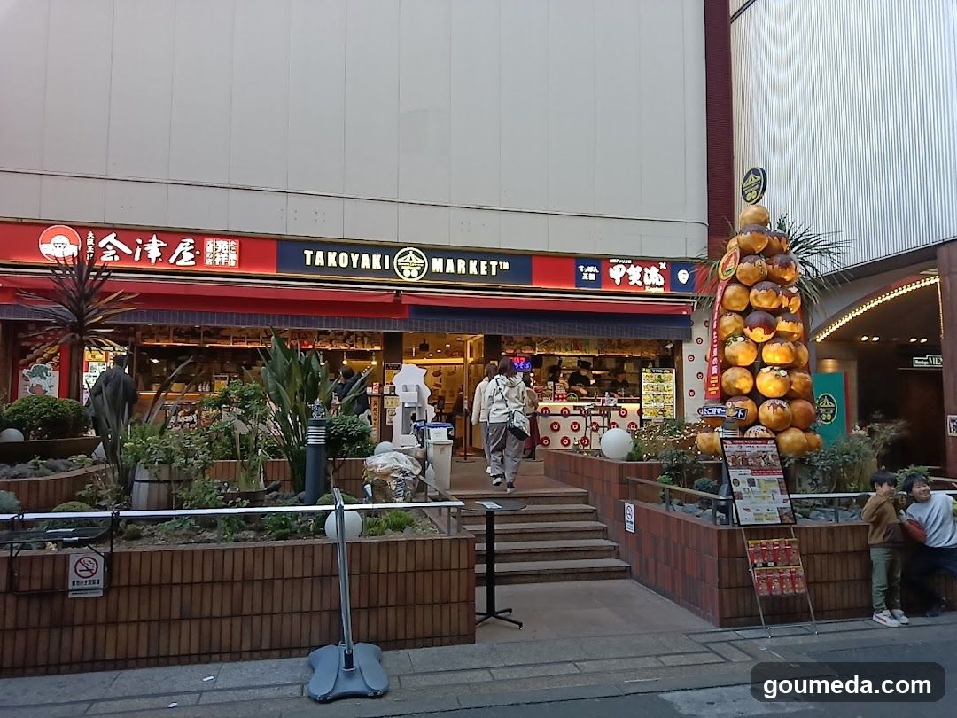 Exterior of Takoyaki Market storefront with visible signage, entrance steps, and decorative elements including a takoyaki tower display.
