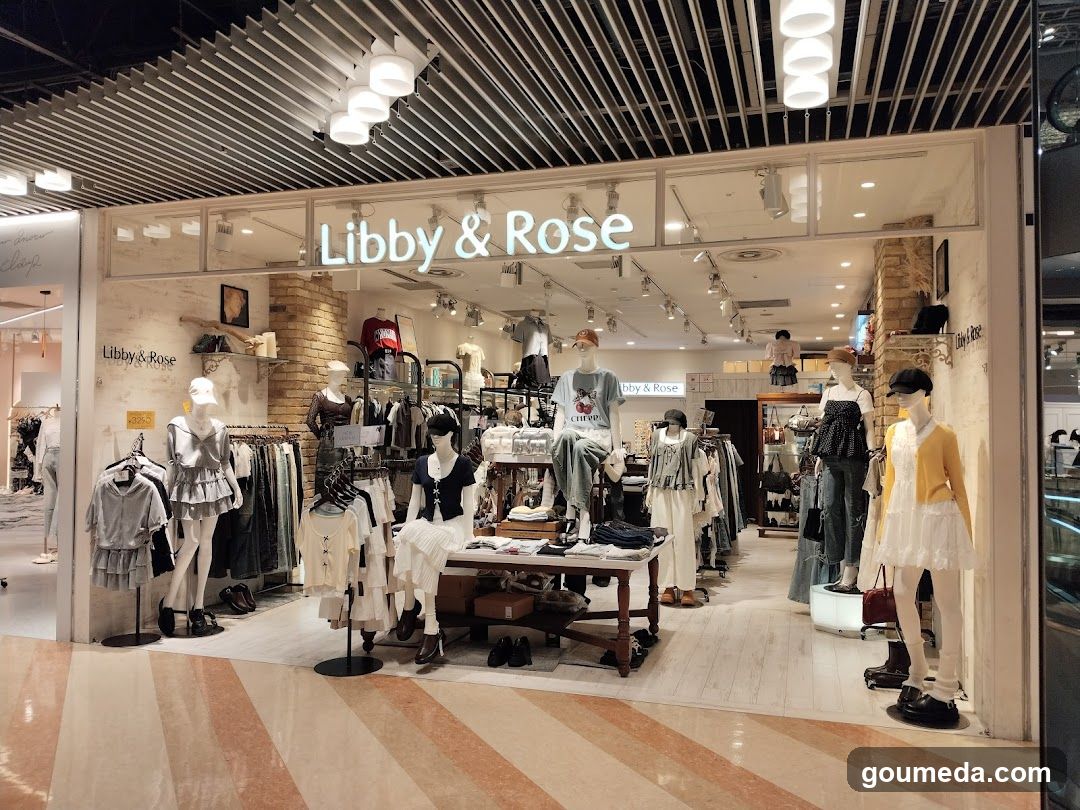A well-lit retail storefront with mannequins displaying clothing items, including dresses and tops. The store name 'Libby & Rose' is prominently displayed above the entrance.