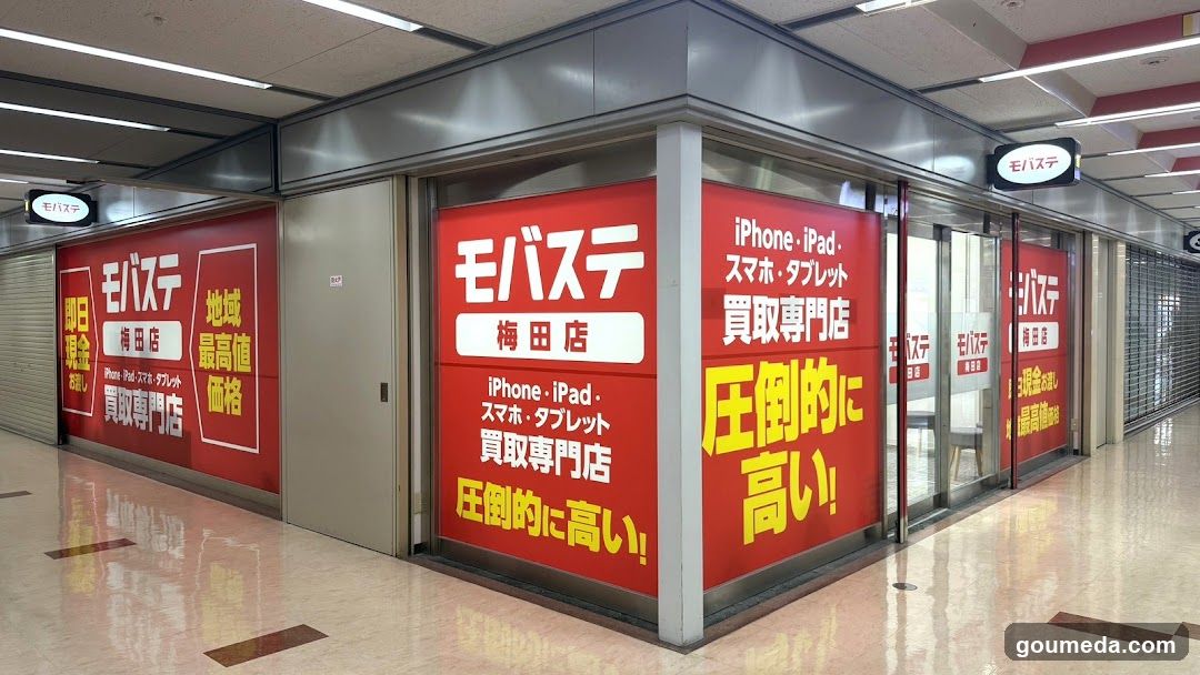 A red storefront with large signage advertising iPhone and iPad trade-in services, featuring bold Japanese text highlighting high prices and regional value.