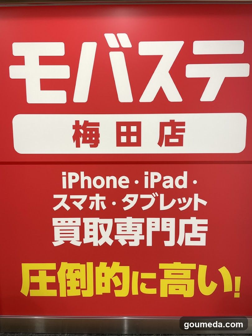 A red storefront sign with white and yellow Japanese text advertising a specialized store for buying iPhones, iPads, smartphones, and tablets. The sign highlights that prices are significantly higher than competitors.