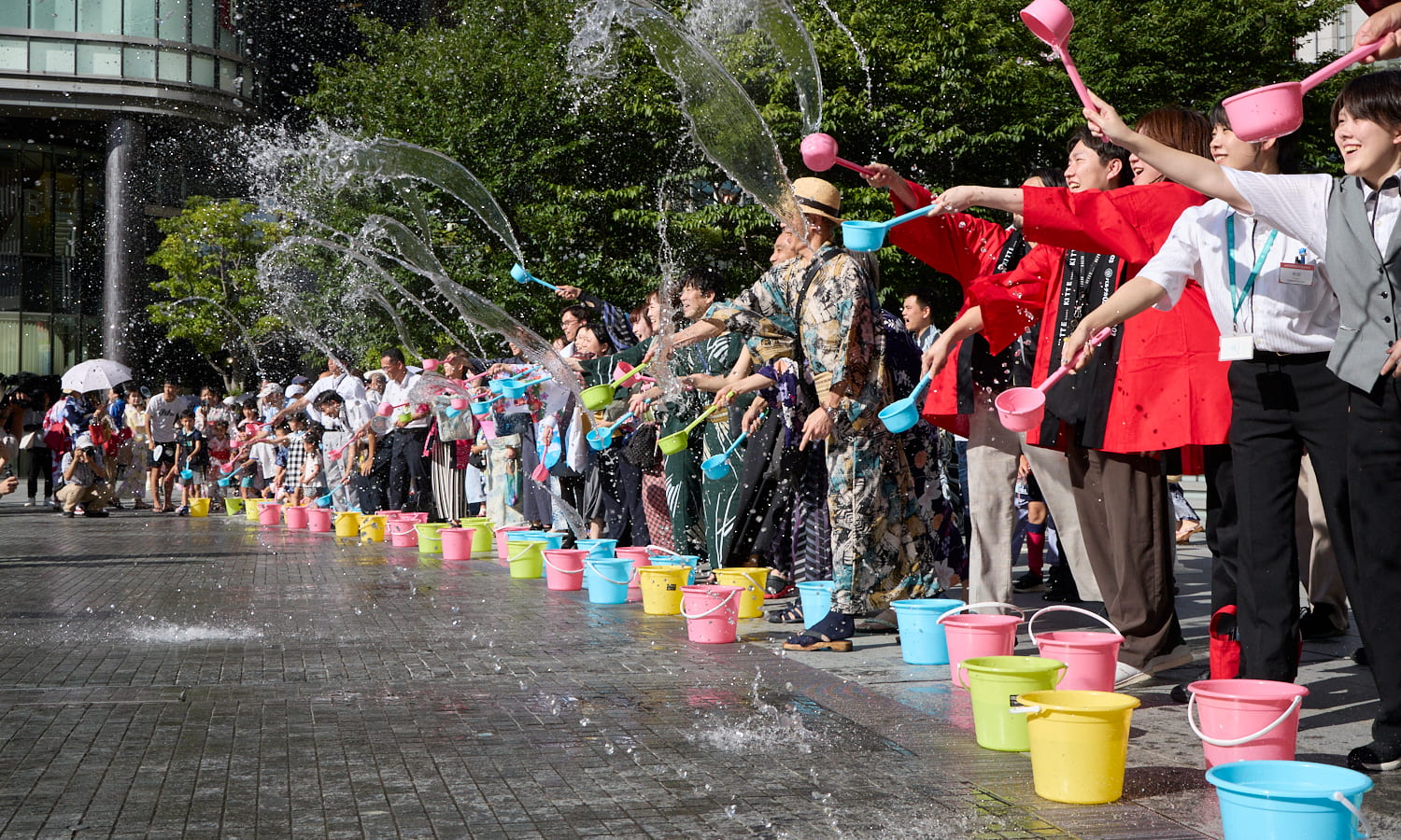 Volunteers sprinkling water on the pavement during the Umeda de Uchimizu event at the Umeda Yukata Festival